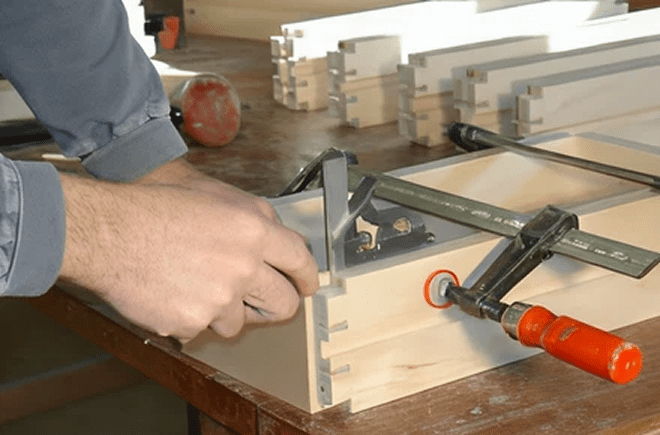 Person measuring wood with square tool.