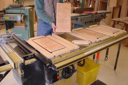 Person assembling wooden cabinet doors on table.
