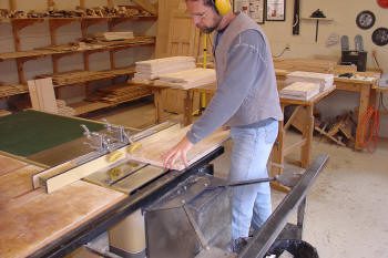 Person using table saw in woodworking shop.