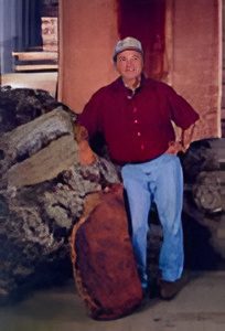 Person standing beside large rocks indoors.