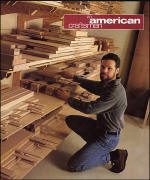 A person kneels in front of stacked wood planks on shelves, organizing or selecting pieces in a workshop. The "American Craft" logo is visible at the top right.