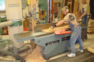 Person operating woodworking machine in workshop.