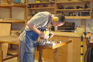 Woodworker using tools in a workshop.