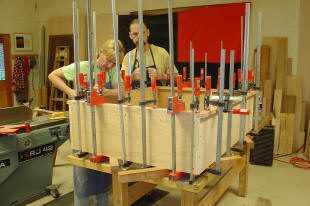 Woodworkers assembling wooden structure with clamps.