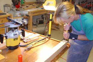 Woman woodworking with chisel in workshop.