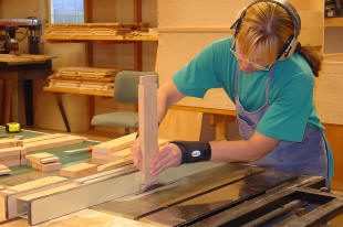Woodworker using a table saw in workshop.