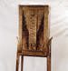 A wooden chair with an intricately carved backrest featuring an abstract geometric design, set against a plain white background.