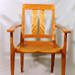 A wooden armchair with vertical slats on the backrest, flat armrests, and four straight legs, set against a plain background.