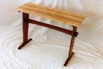 A small wooden table with a light-colored rectangular top and dark wooden legs, placed on a white surface.