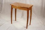 Small wooden side table with four slender, curved legs and a rectangular top, set against a plain, light-colored background.