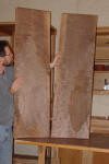 Person holding two large wooden boards.
