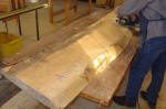 Woodworker sanding large wooden slab.