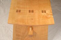 A close-up view of a wooden birdhouse with a slanted roof, featuring three rectangular vents near the roof edge.
