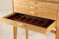 A wooden dresser with an open drawer featuring multiple compartments for organizing small items. The dresser has a light wood finish and four legs.