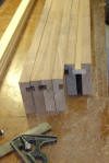 Four wooden boards with mortise and tenon joints cut at the ends are arranged on a workbench next to a combination square.