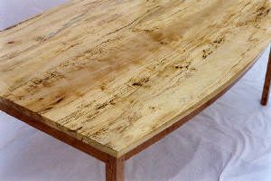 A close-up view of a wooden table with a light, natural finish and visible grain patterns, placed on a white surface.