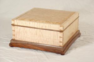 A square wooden box with dovetail joints, light-colored top and sides, and a darker wood base, placed on a white background.