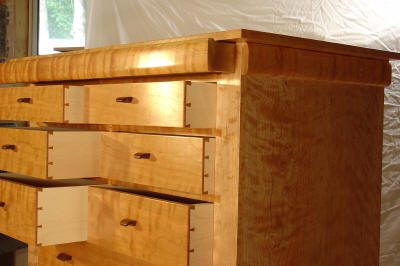 A wooden dresser with multiple drawers, some of which are partially open, set against a white backdrop.