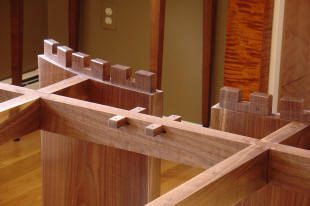 Close-up of wooden joinery featuring dovetail and mortise-and-tenon joints in a partially assembled piece of furniture.
